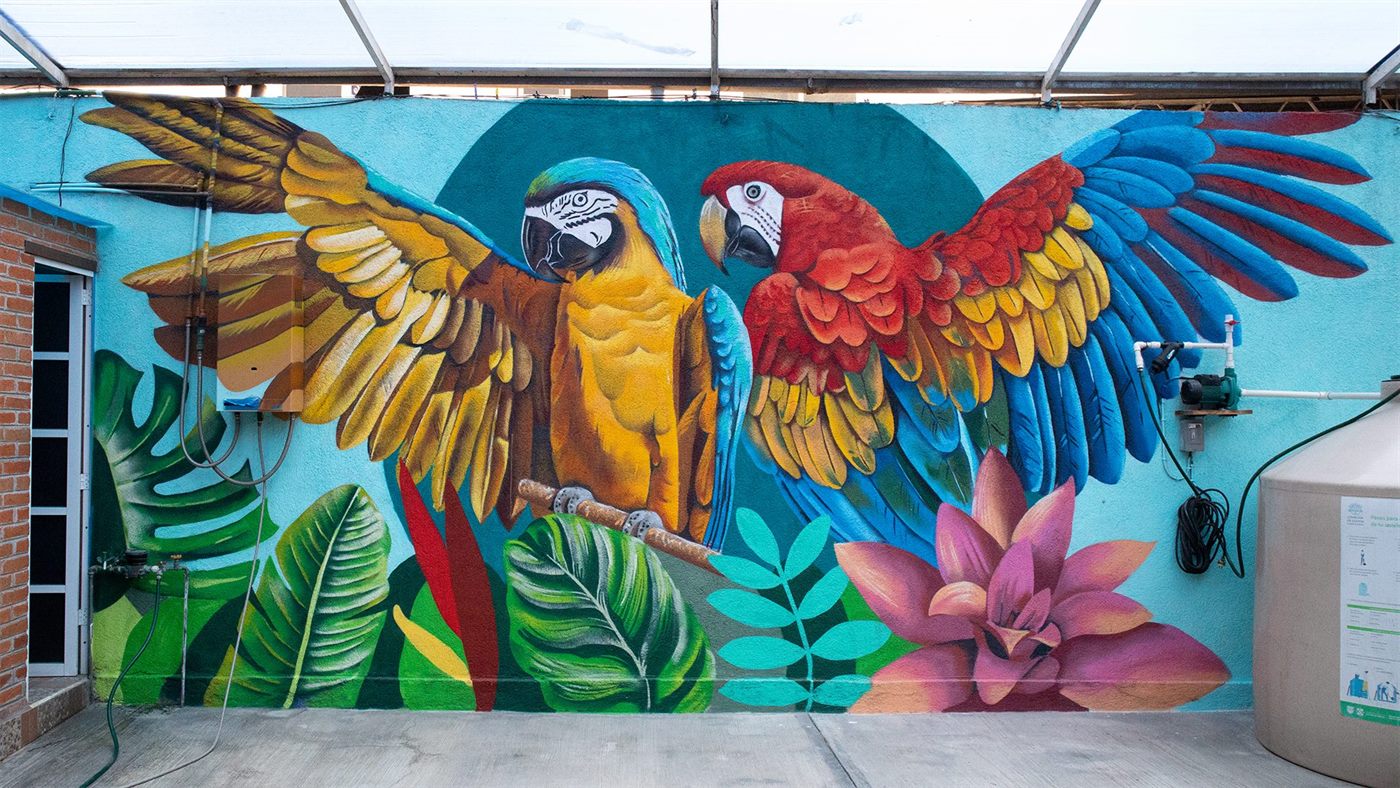 Mural de dos guacamayas con las alas abiertas sobre la terraza de un bar